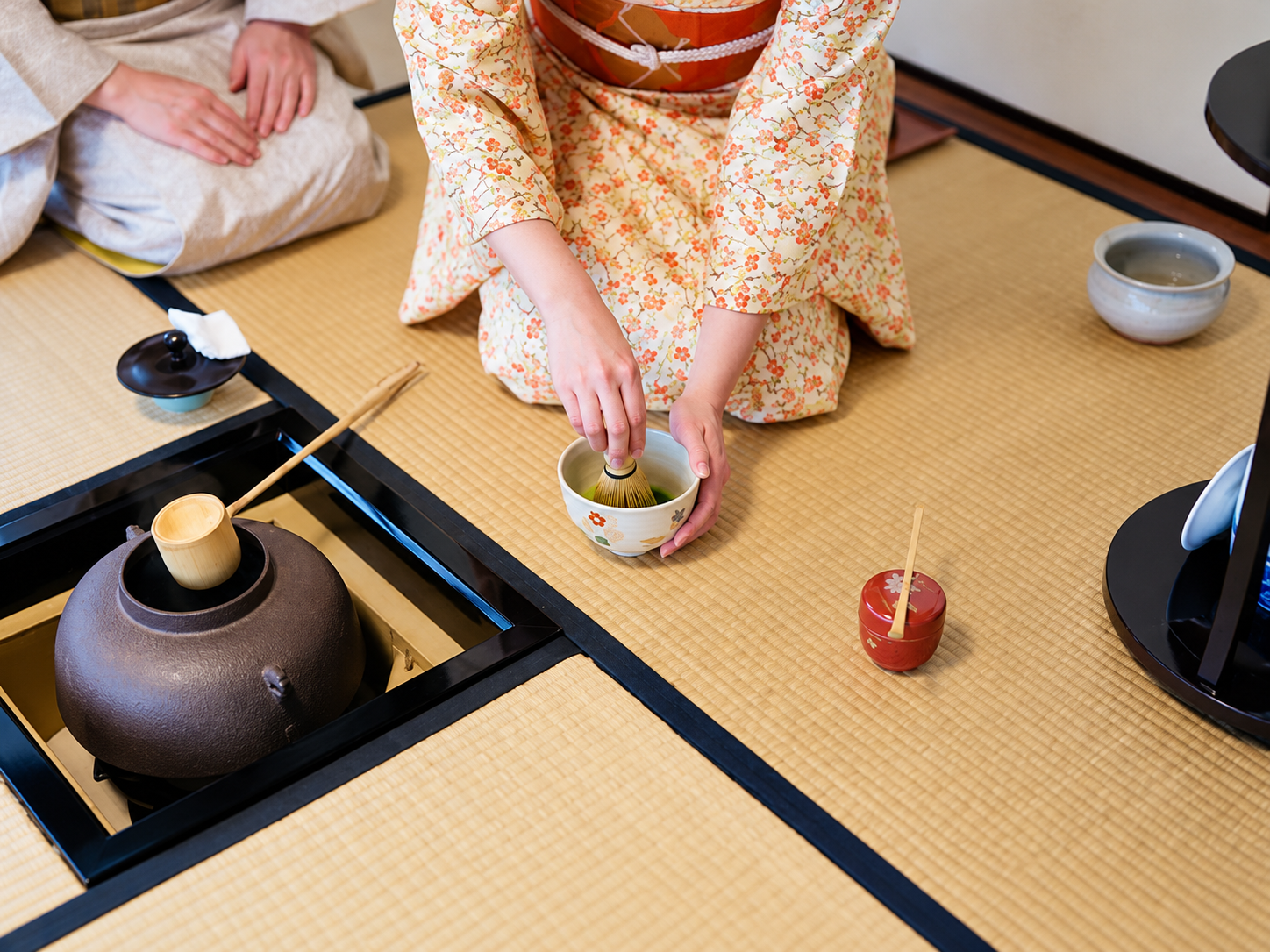 畳の上で茶筅を使って抹茶を点てる手元と茶道具